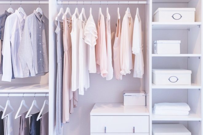 clothes hanging on rail in white wardrobe with boxes